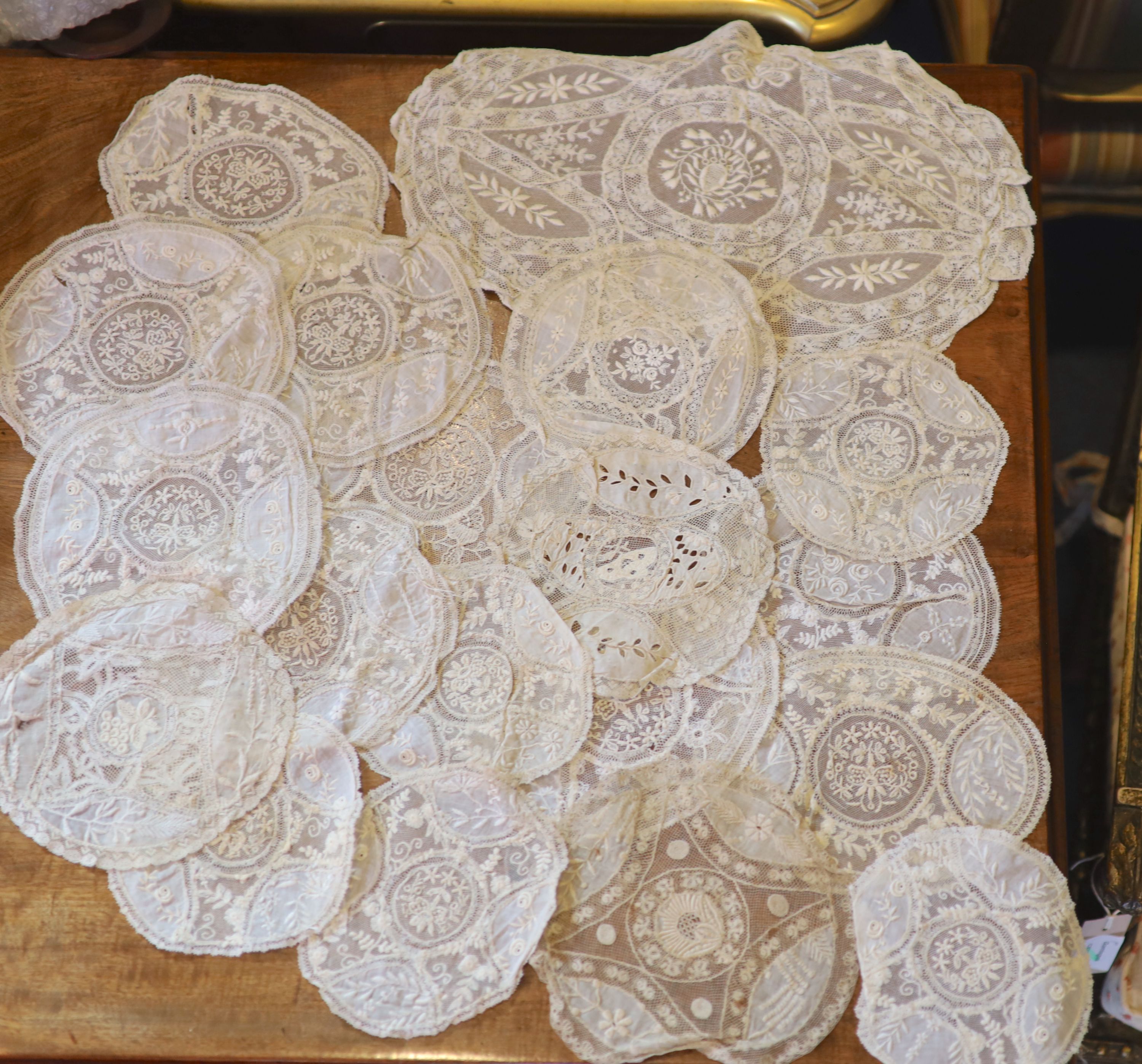 A square Normandy lace table cloth and approximately nineteen circular place mats and a centrepiece,